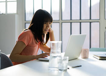 Businesswoman using laptop on table while working at home office - GIOF12375