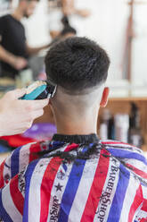 Männlicher Friseur benutzt eine Maschine, um die Frisur eines Teenagers zu stylen - JRVF00412