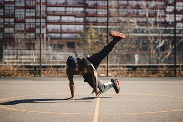 African man doing acrobatic activity on basketball court - GUSF05741