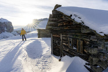 Wanderer in der verschneiten Landschaft im Gegenlicht des Sonnenuntergangs im Winter, Grödnerjoch, Dolomiten, Südtirol, Italien, Europa - RHPLF19399