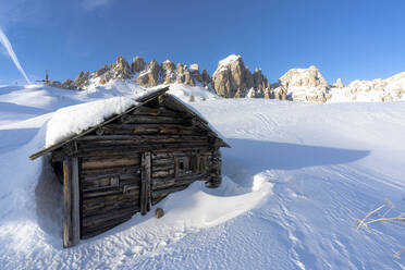 Einsame, verschneite Holzhütte mit den Gipfeln der Cir-Gruppe im Hintergrund bei Sonnenuntergang, Grödnerjoch, Dolomiten, Südtirol, Italien, Europa - RHPLF19542