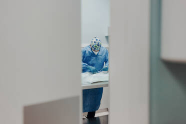 Focused male veterinarian in uniform and respiratory mask using medical instruments during surgery in hospital - ADSF22629