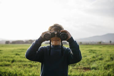 Smiling boy with binoculars in field - JRFF05126