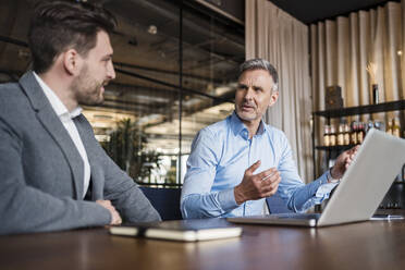 Male entrepreneurs with laptop planning strategy in board room at office - DIGF15125