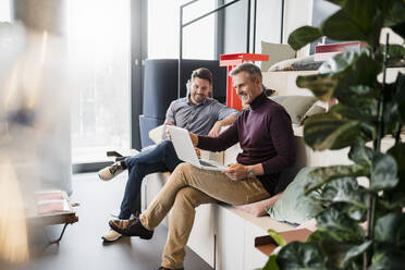 Lächelnde Geschäftsleute, die an einem Laptop am Arbeitsplatz arbeiten - DIGF15168