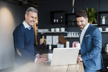 Geschäftsleute arbeiten an einem Laptop in einem Bürocafé - DIGF15189