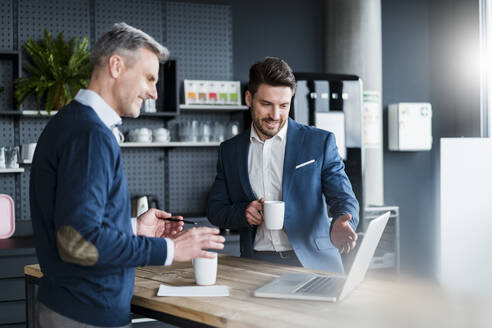 Geschäftsleute diskutieren am Laptop bei einem Kaffee im Bürocafé - DIGF15190