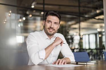 Nachdenklicher Geschäftsmann im mittleren Erwachsenenalter, der bei der Arbeit in einem Büro wegschaut - DIGF15219