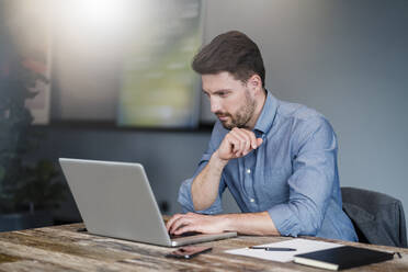 Mittlerer erwachsener männlicher Unternehmer arbeitet am Laptop über dem Tisch im Büro - DIGF15240