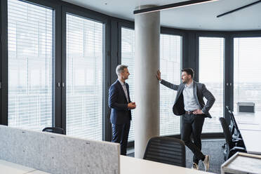 Business people talking while standing by architectural column in office - DIGF15260