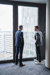 Geschäftsleute diskutieren am Fenster stehend im Büro - DIGF15266