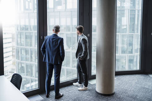 Geschäftsmann und Unternehmer schauen durch ein Fenster im Büro - DIGF15267