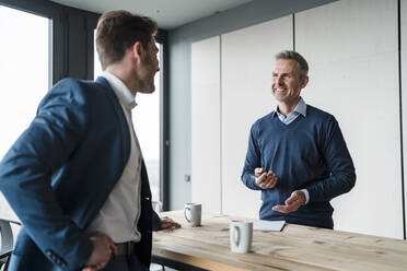 Lächelnde Geschäftsleute diskutieren am Tisch im Büro-Café - DIGF15282