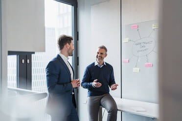 Smiling businessmen in meeting discussing by whiteboard at work place - DIGF15289