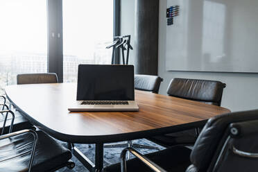 Leerer Laptop auf Konferenztisch inmitten von Stühlen im Büro - DIGF15300