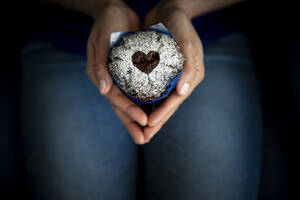 Hände einer Frau, die einen Muffin zum Valentinstag hält - MBEF01468