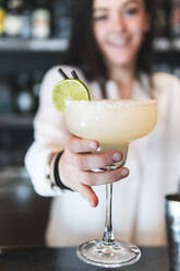 Barkeeperin gibt Cocktail am Tresen - JAQF00479