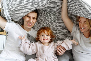 Familie spielt unter einer Decke auf dem Bett zu Hause - VYF00537