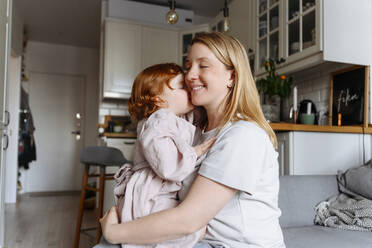 Lächelnde schwangere Frau umarmt Tochter in der Küche zu Hause - VYF00565
