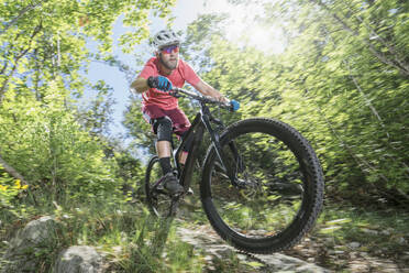 Man riding bicycle on footpath in forest - RNF01324