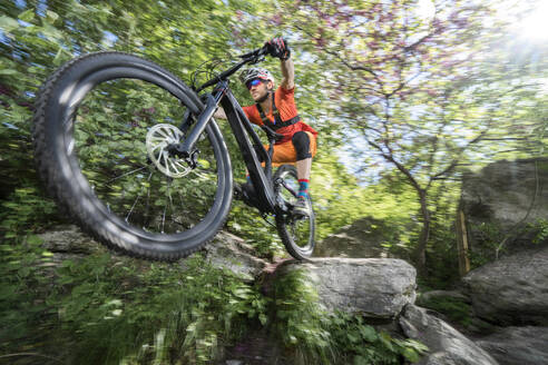 Männlicher Sportler fährt Fahrrad auf einem Felsen im Wald - RNF01329