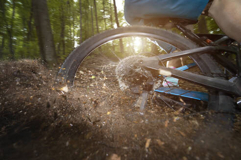 Hinterrad eines Fahrrads driftet auf einem unbefestigten Weg im Wald - RNF01330