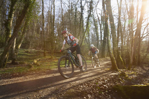 Radfahrerinnen fahren auf einem unbefestigten Weg im Wald - RNF01332