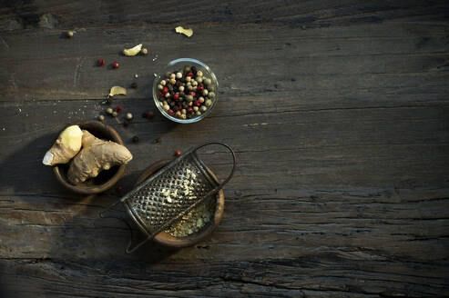 Bowls with ginger root, old grater and various peppercorns lying on wooden surface - ASF06747