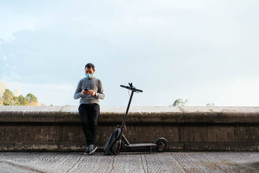 Man using smartphone near electric scooter - CAVF93768