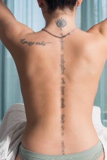Junge Frau mit nacktem Rücken, die sich auf eine therapeutische Massage vorbereitet - CAVF93806
