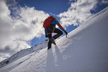 Ein Mann besteigt an einem sonnigen Tag einen verschneiten Berg in Devero, Italien. - CAVF93882