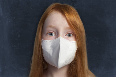 Redhead girl wearing protective face mask against black background - GAF00149