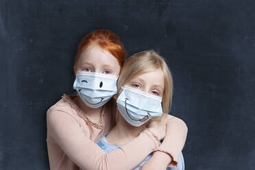 Sisters embracing while wearing protective face mask - GAF00153
