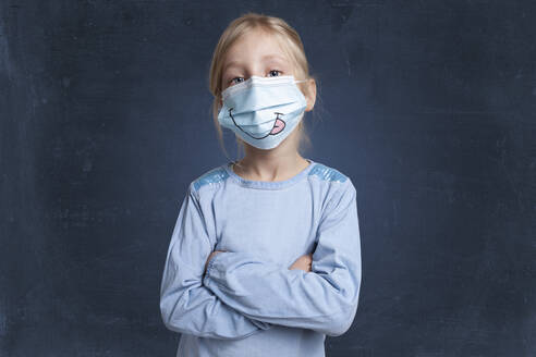 Girl with arms crossed wearing face mask against black background - GAF00166