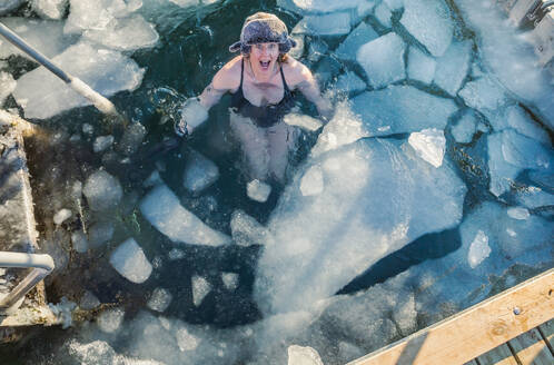 Amerikanische Frau Mitte 40, aufgeregt über das Schwimmen mit Eis in Dänemark - CAVF93921