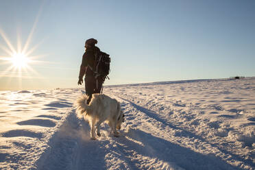 Man with dog trekking in winter snow - CAVF93933