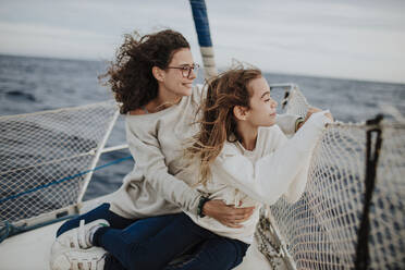 Mutter und Tochter betrachten die Aussicht während der Fahrt mit dem Segelboot auf dem Meer im Urlaub - GMLF01170