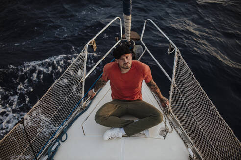Mann genießt seinen Urlaub auf einem Segelboot im Meer sitzend - GMLF01183