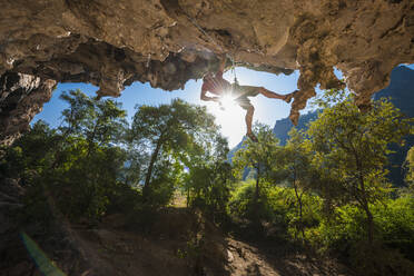 Man climbing on overhanging limestone cliff in Laos - CAVF93959