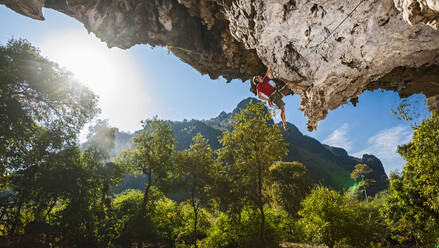 Man climbing on overhanging limestone cliff in Laos - CAVF93961