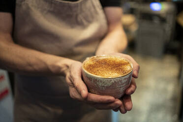 Barista holding coffee cup at cafe - FBAF01810