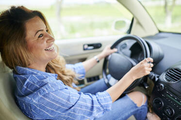 Glückliche Frau schaut beim Autofahren weg - KIJF03726