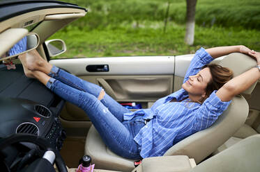 Mid adult woman resting in convertible car - KIJF03732