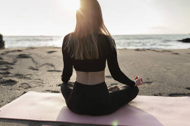 Frau sitzt und macht Yoga am Strand - JPTF00736