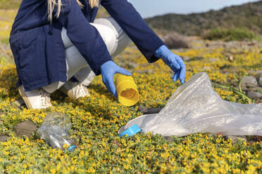 Frau sammelt Plastikmüll an einem sonnigen Tag - JPTF00747