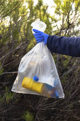 Frau mit Schutzhandschuh hält Plastikmüllsack - JPTF00748