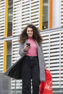 Lächelnde Frau mit Tasche und Mobiltelefon - PNAF01454