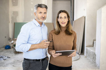 Weiblicher Kollege mit digitalem Tablet neben einem gut aussehenden männlichen Architekten auf der Baustelle - PESF02800