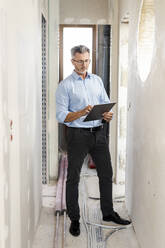 Male professional using digital tablet in corridor at construction site - PESF02811