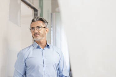 Male architect with eyeglasses looking away at construction site - PESF02813